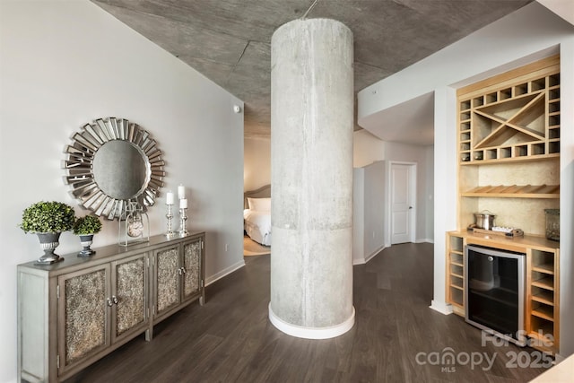 indoor dry bar with beverage cooler, dark wood finished floors, and baseboards