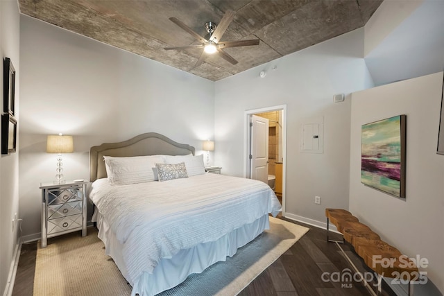 bedroom featuring wood finished floors, electric panel, baseboards, ensuite bath, and a ceiling fan
