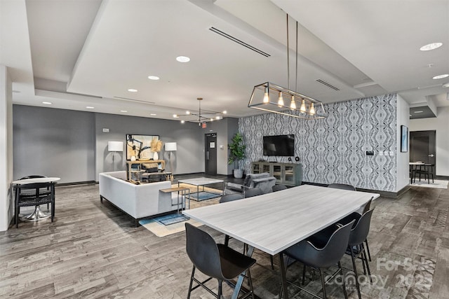 dining space with baseboards, wood finished floors, an accent wall, and recessed lighting