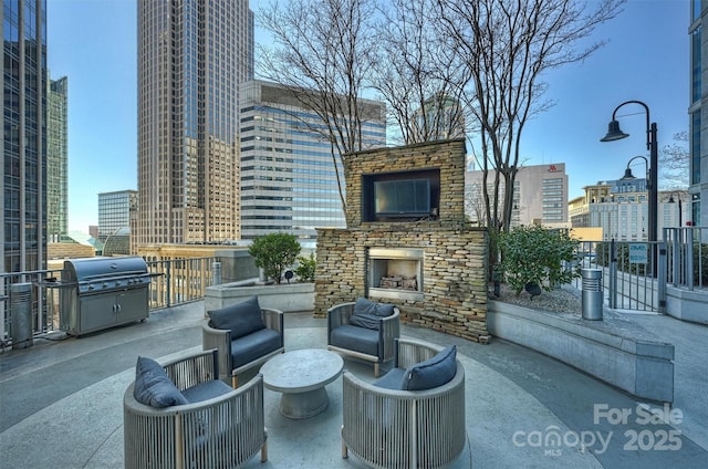 view of patio / terrace with an outdoor stone fireplace, a grill, and a view of city