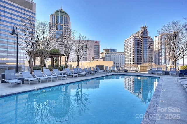 community pool with an outdoor living space, a view of city, and a patio