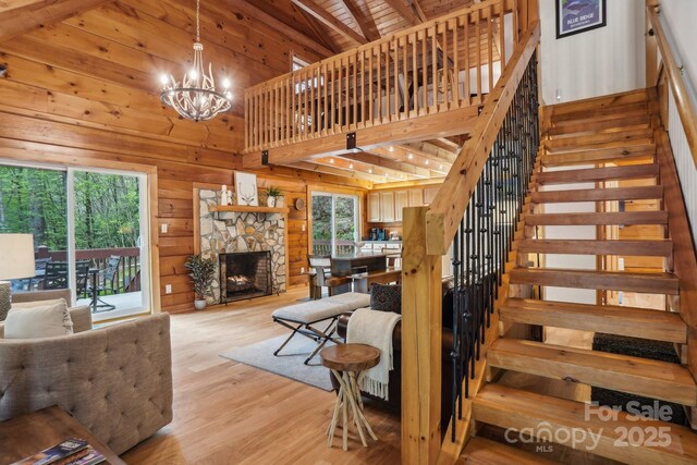 909 Niley Cook Rd, Blowing Rock, NC 28605 - stairway with a notable chandelier, wood walls, high vaulted ceiling, wood finished floors, and a fireplace