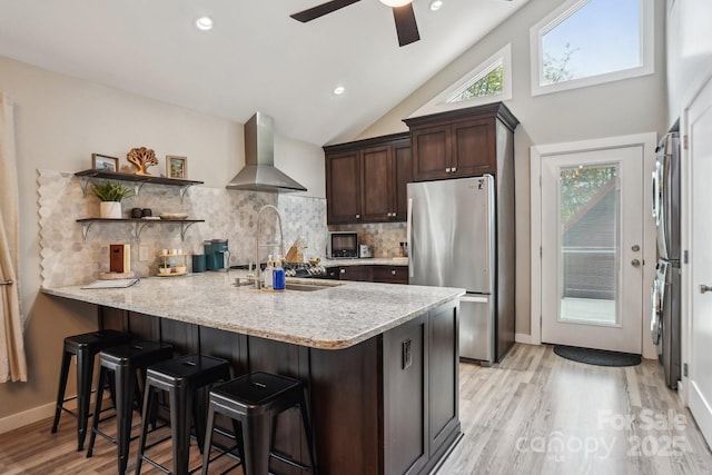 909 Niley Cook Rd, Blowing Rock, NC 28605 - kitchen featuring a peninsula, freestanding refrigerator, wall chimney exhaust hood, dark brown cabinetry, and a ceiling fan