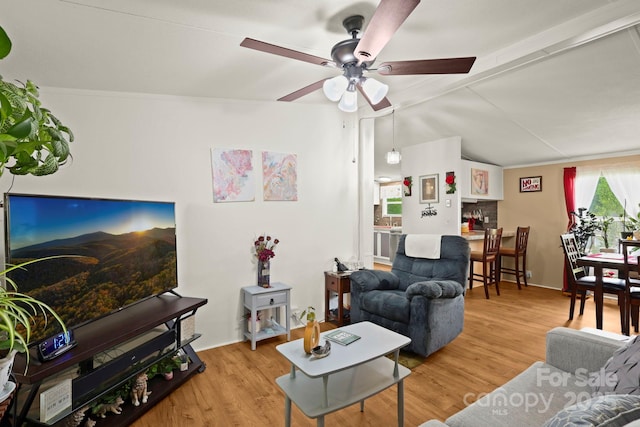 living area featuring lofted ceiling with beams, ceiling fan, and wood finished floors