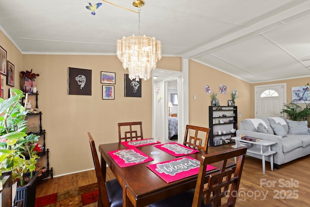 dining room with crown molding, a chandelier, wood finished floors, and lofted ceiling