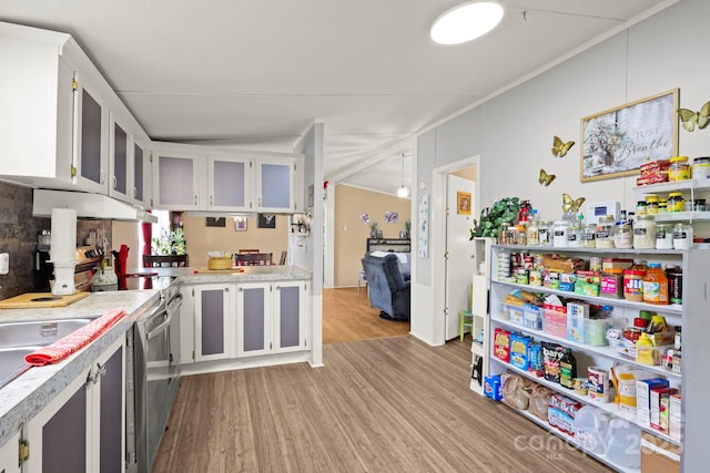 kitchen with under cabinet range hood, glass insert cabinets, light wood-style floors, light countertops, and white cabinets