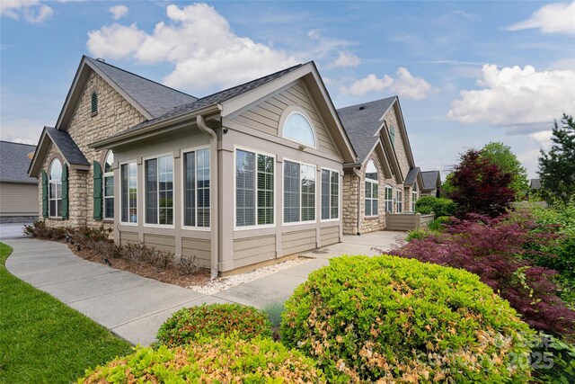 33 Braeburn Way, Flat Rock, NC 28731 - view of side of home featuring a patio area, a shingled roof, and stone siding