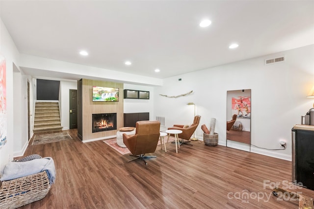 living room featuring wood finished floors, baseboards, a glass covered fireplace, and recessed lighting