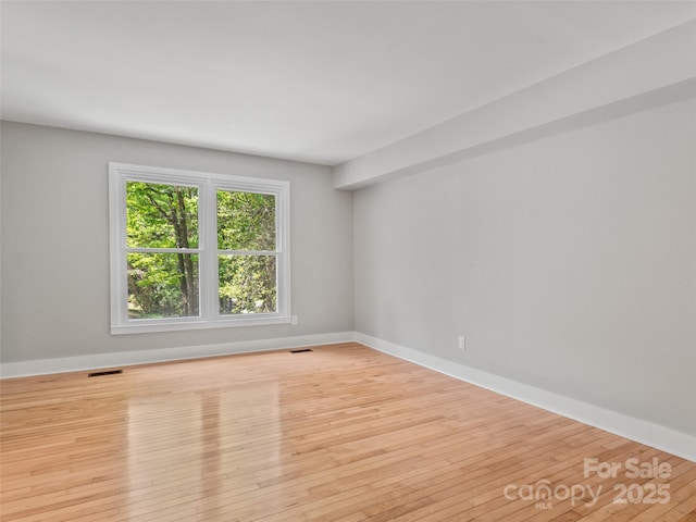 spare room with wood-type flooring and baseboards