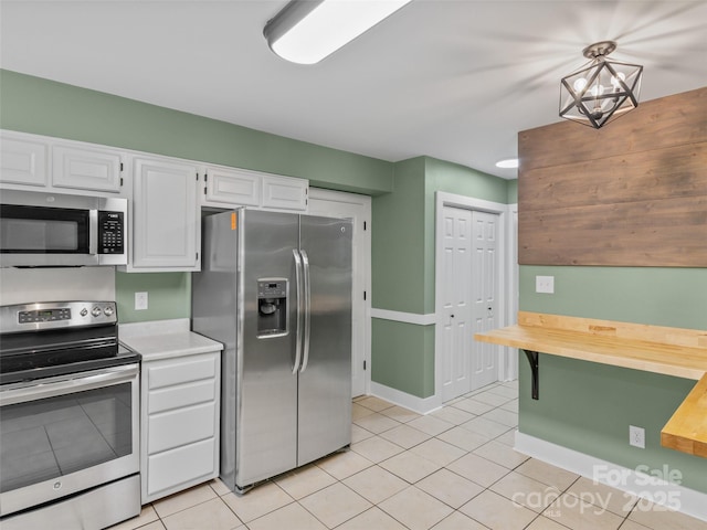 kitchen with appliances with stainless steel finishes, white cabinetry, and light tile patterned floors