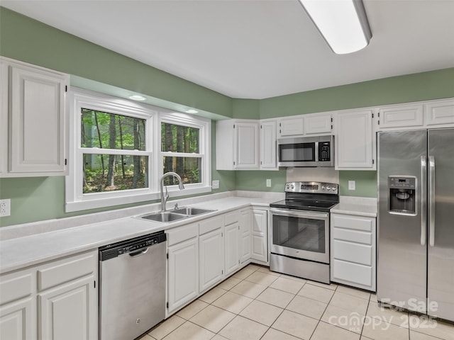 kitchen featuring appliances with stainless steel finishes, a sink, light countertops, white cabinetry, and light tile patterned floors