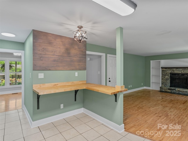 kitchen with wooden counters, baseboards, built in shelves, a kitchen bar, and light tile patterned flooring