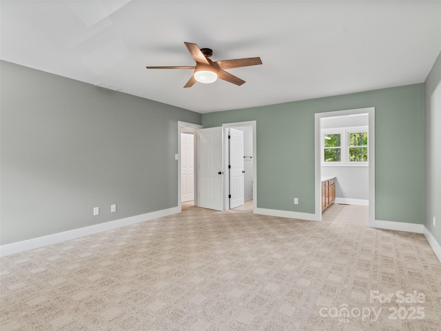 unfurnished bedroom with light carpet, baseboards, ensuite bath, and a ceiling fan
