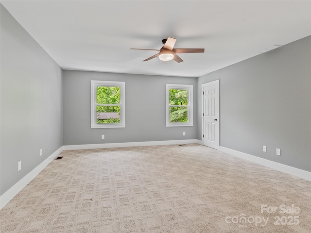 carpeted empty room featuring a ceiling fan, plenty of natural light, and baseboards