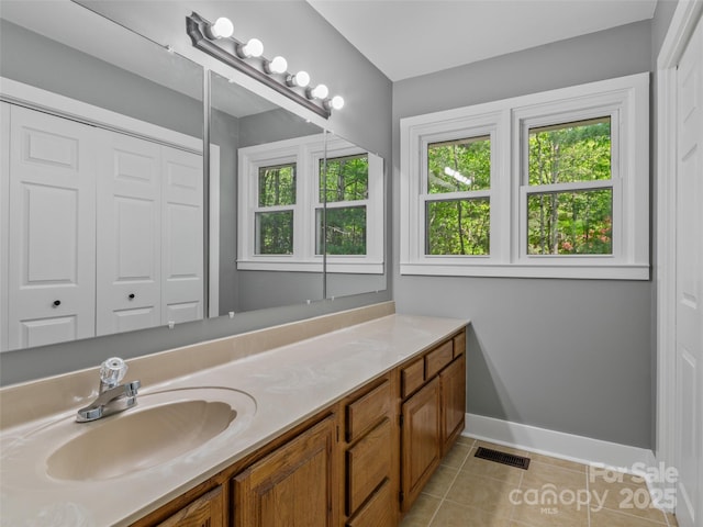 bathroom with tile patterned flooring, baseboards, plenty of natural light, and vanity