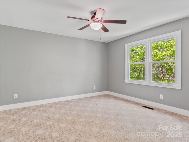 carpeted spare room featuring a ceiling fan and baseboards