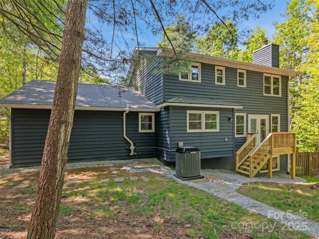 rear view of house featuring central AC, a chimney, stairs, and fence