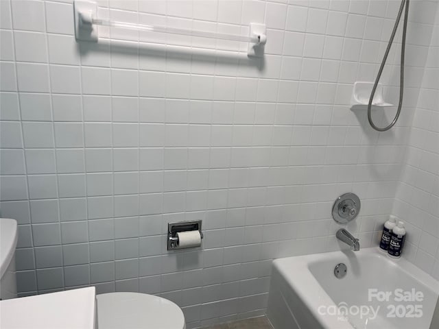 full bathroom featuring toilet, washtub / shower combination, and tile walls
