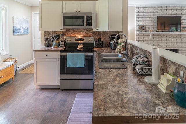 kitchen featuring ornamental molding, a sink, decorative backsplash, appliances with stainless steel finishes, and dark wood-style floors
