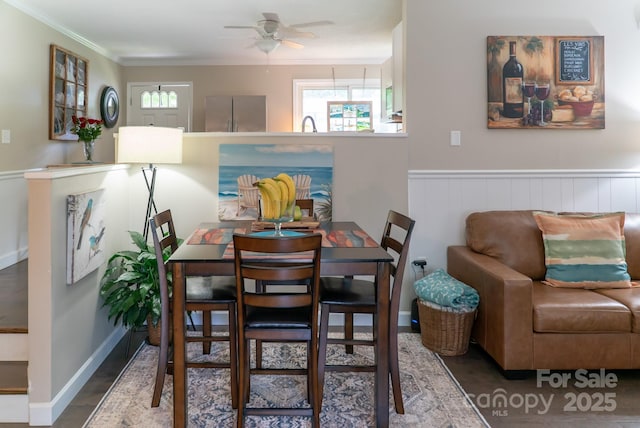 dining space featuring wainscoting, wood finished floors, a ceiling fan, and ornamental molding