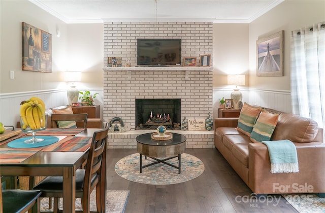 living room with crown molding, wood finished floors, wainscoting, and a fireplace