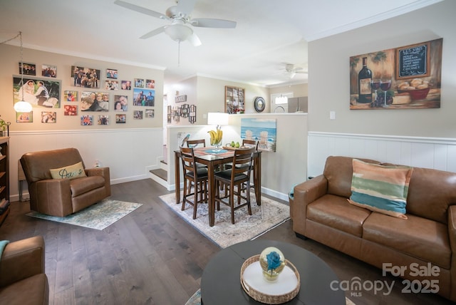 living area with wainscoting, ceiling fan, ornamental molding, and wood finished floors