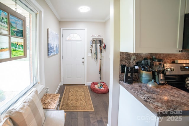 interior space featuring crown molding, baseboards, plenty of natural light, and wood finished floors
