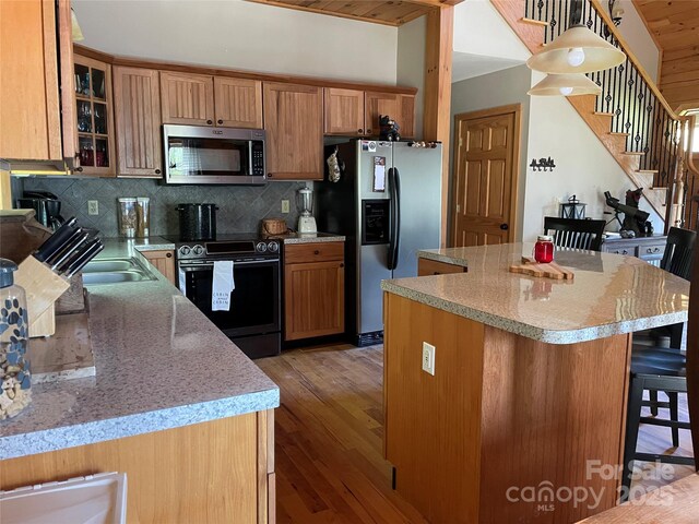 96 Trails End Ln, Maggie Valley, NC 28751 - kitchen with stainless steel appliances, tasteful backsplash, a kitchen bar, light wood-style floors, and a kitchen island