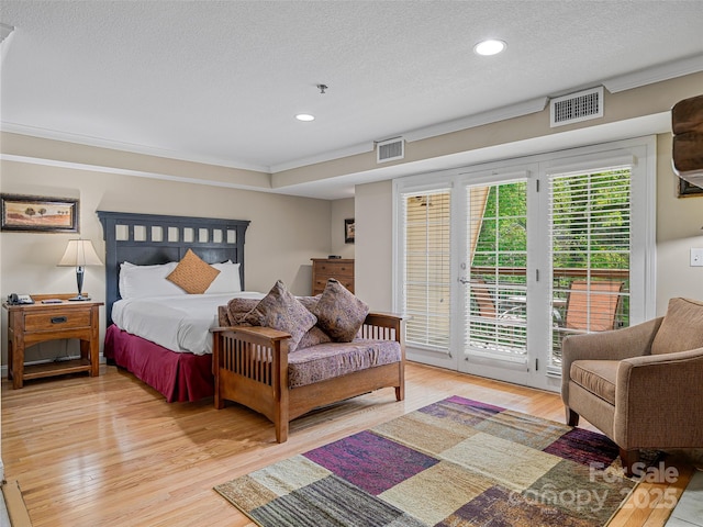bedroom featuring a textured ceiling, light wood-type flooring, visible vents, and access to exterior