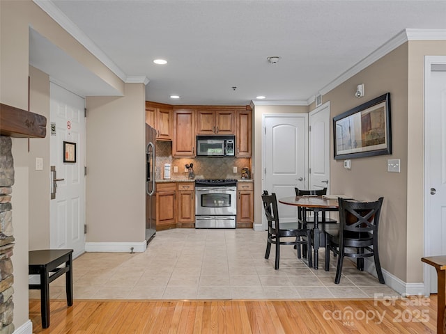 kitchen with crown molding, stainless steel appliances, tasteful backsplash, and brown cabinets