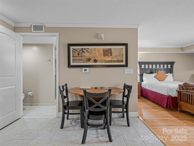 dining room featuring crown molding, baseboards, light tile patterned floors, and visible vents