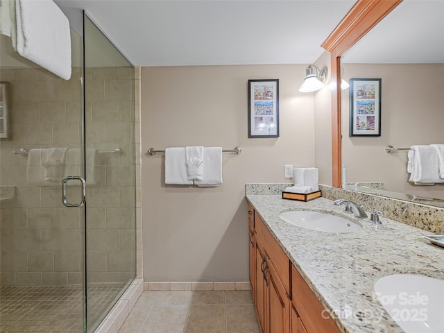 full bath featuring a stall shower, baseboards, a sink, tile patterned floors, and double vanity