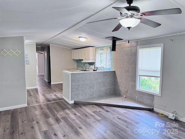 unfurnished living room with a ceiling fan, a sink, plenty of natural light, and wood finished floors