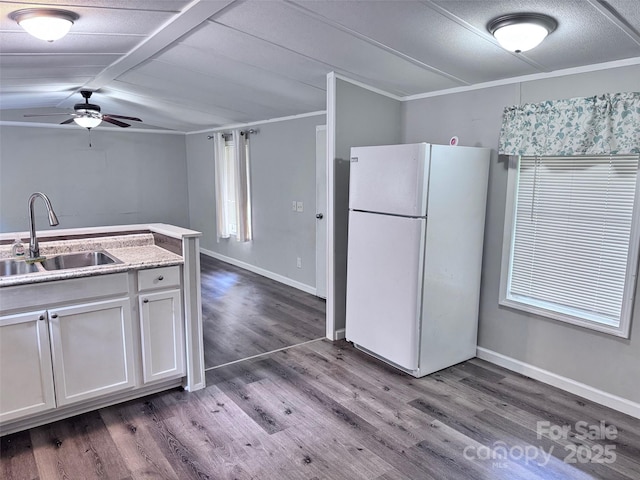kitchen with a sink, freestanding refrigerator, dark wood finished floors, ceiling fan, and white cabinets