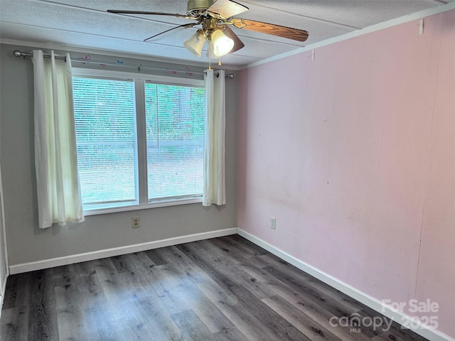empty room featuring ceiling fan, ornamental molding, baseboards, and wood finished floors