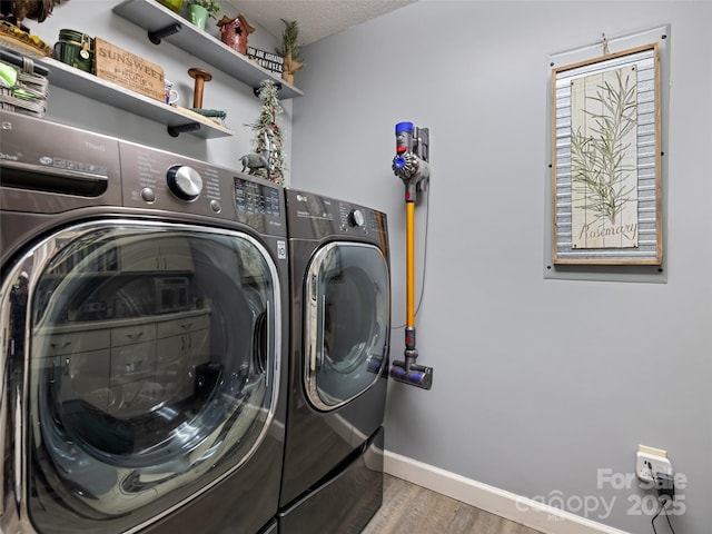 laundry room with baseboards, laundry area, wood finished floors, and washer and clothes dryer