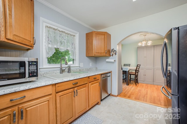 kitchen featuring a sink, crown molding, an inviting chandelier, arched walkways, and appliances with stainless steel finishes