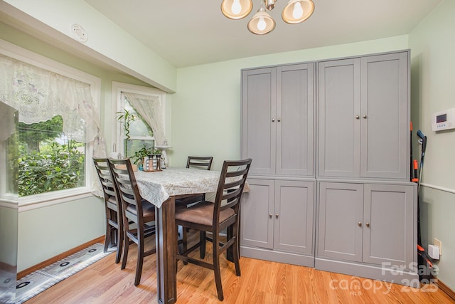 dining space with baseboards, light wood finished floors, and an inviting chandelier