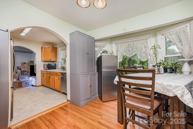 dining area featuring arched walkways and light wood-style floors