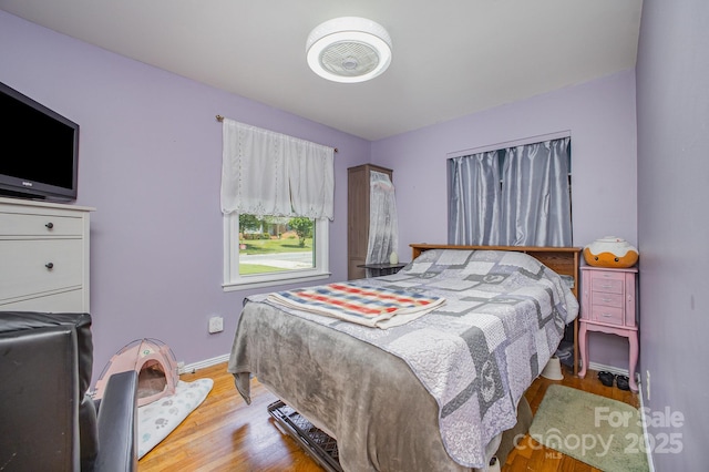 bedroom featuring light wood finished floors and baseboards