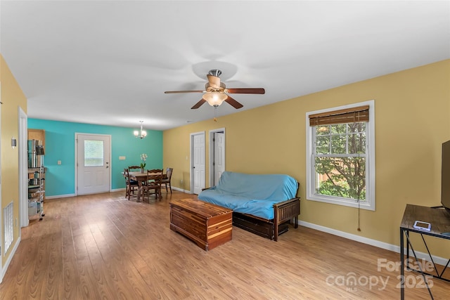 living room with light wood-style flooring, baseboards, ceiling fan, and a chandelier
