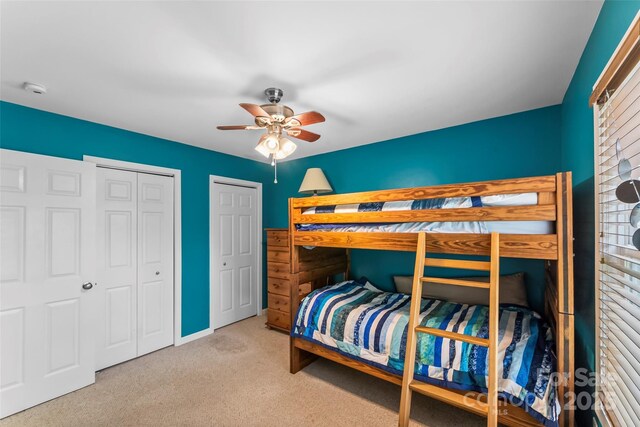 carpeted bedroom featuring multiple closets and a ceiling fan