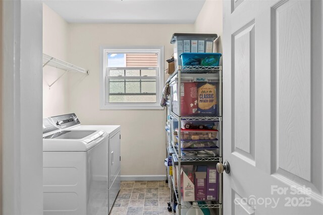 laundry area featuring washing machine and clothes dryer, baseboards, and light stone finish flooring