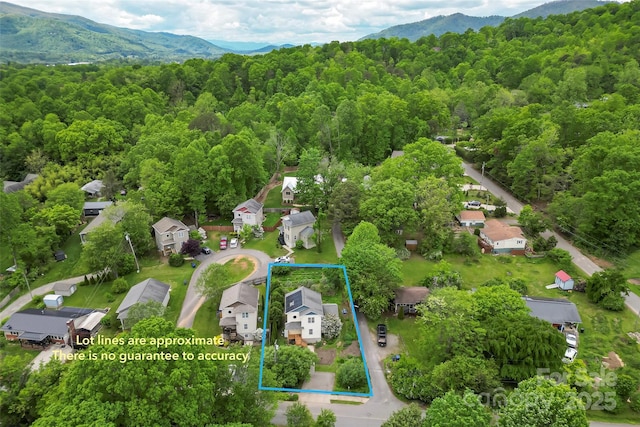 view of property location with a heavily wooded area, property parcel outlined, and a mountain backdrop