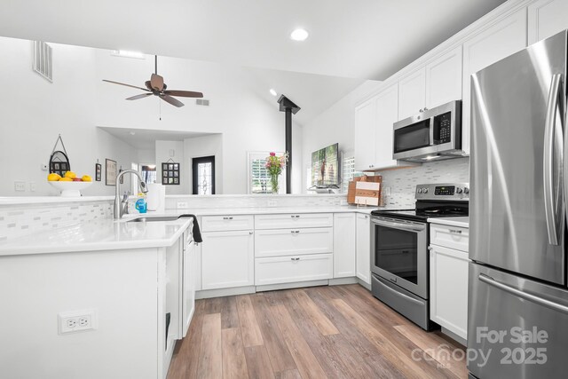 kitchen featuring stainless steel appliances, recessed lighting, a ceiling fan, decorative backsplash, and a peninsula