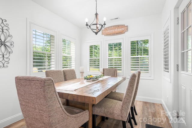 dining room with a chandelier, light wood-style flooring, and baseboards