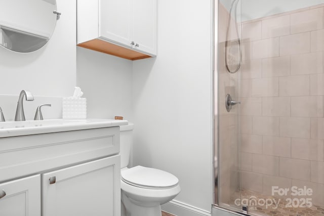 bathroom featuring a shower stall, toilet, and vanity