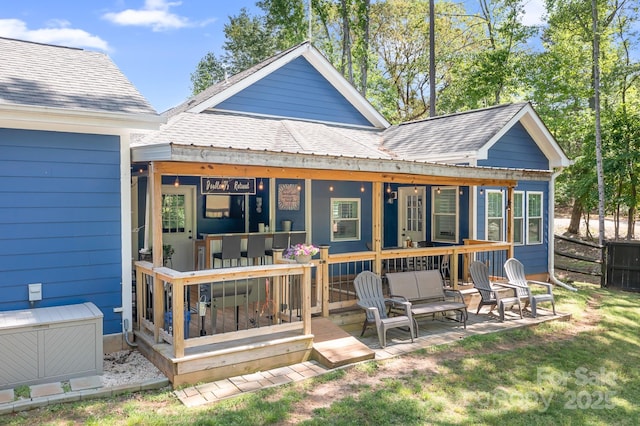 back of property featuring a shingled roof, fence, and a wooden deck