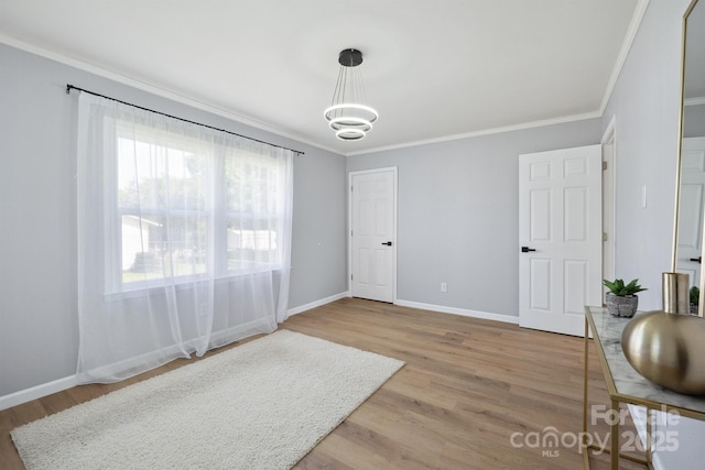 interior space with ornamental molding, a notable chandelier, and light wood-style floors