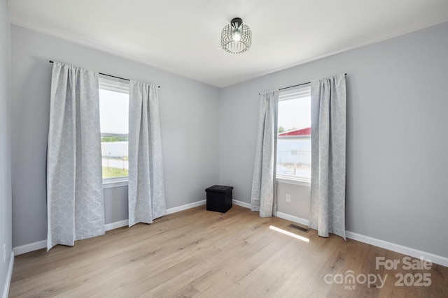 spare room with visible vents, wood finished floors, and baseboards